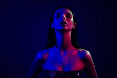 Neon ışıklarıyla aydınlatılmış güzel genç bir kadın göz alıcı ve şık bir kompozisyonu olan mavi ve kırmızı renklerin bir karışımını oluşturuyor..