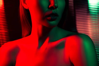 Dinamik kırmızı ve yeşil ışık aksanıyla çevrili karanlık bir ortamda genç bir kadının yer aldığı canlı ışıklandırma sanatı.