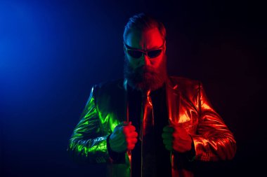 Olgun, sakallı bir adam parlak bir elbiseyle karizma yayar. Parlak ışıklar saçar. Renkli ışıltılar saçar..