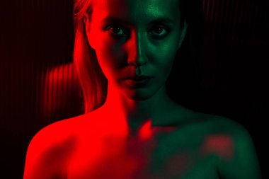 Kırmızı ve yeşil neon ışıkla aydınlatılmış genç bir kadının büyüleyici bir portresi, canlı modern sanatsal tarzda gizem, zerafet ve cazibe hissi uyandırıyor..