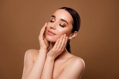 Bej renkli arka planda izole edilmiş yumuşak tenin tadını çıkaran rüya gibi, çarpıcı çıplak omuzların portresi..