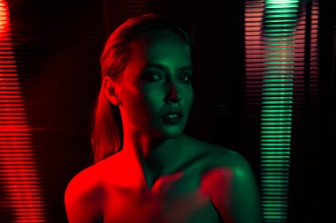 Canlı kırmızı ve yeşil ışıkların vurgulandığı genç bir kadın modelin portresi şık bir moda ve gece hayatı yaratıyor..