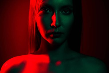 Kırmızı ve yeşil renklerde dramatik ışıklandırma gösteren, modern moda, güzellik ve sanatsal ruh halini vurgulayan bir kadın portresi. Cazibe, gece hayatı ve yaratıcı görsel temalar için uygundur..