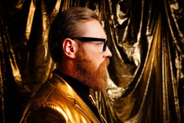 Kırmızı saçlı ve sakallı, altın takım elbiseli, şık ve kendinden emin bir adam. Tatil ve moda temaları için mükemmel..