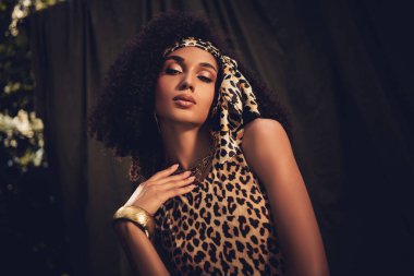Leopar desenli bir elbise giyen genç bir kadının zarif portresi şık moda tarzını ve güzelliğini gözler önüne seriyor..