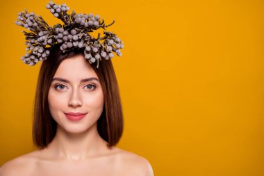 Kafasına çiçekli bir aksesuar takmış güzel bir genç kadının yakın plan portresi canlı sarı bir arka plana poz vererek baharı, doğal güzelliği ve pozitif enerjiyi sembolize ediyor..