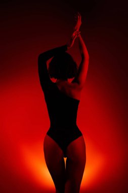 Çağdaş bir tasvirde genç bir kadın zarif bir şekilde poz veriyor, mayo giyiyor, sarı ve turuncu tonlarda değişen bir ışığa karşı, şehvet, tarz ve modern sanatsal ifade ile ifade ediliyor..