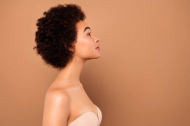 Göz kamaştırıcı, nazik, pürüzsüz, saf tenli, bej renkli arka planda izole edilmiş bir kadının profil tarafı fotoğrafı..