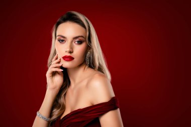 Şık bir genç kadın, göz alıcı bir makyajla ve büyüleyici bir ifadeyle göz kamaştırıcı kırmızı bir arka planda güzelliğini sergiliyor..