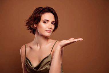 Avuç içi boşluğu olan güzel bir bayanın fotoğrafı kahverengi arka planda izole edilmiş moda haki rengi kıyafet..