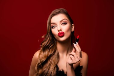 Güzel kız arkadaşının fotoğrafı ruj tutarken kırmızı arka planda hava öpücüğü gönderiyor..