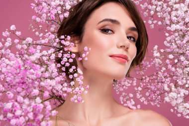 Göz kamaştırıcı, çıplak kadın portresi. Vahşi çiçeklerin aromasının tadını çıkar. Pembe arka plan..