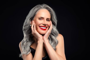 Tarz sahibi, gri saçlı, parlak kırmızı rujlu, esmer, esmer, kendine güvenini ve entelektüelliğini ifade eden bir kadın..