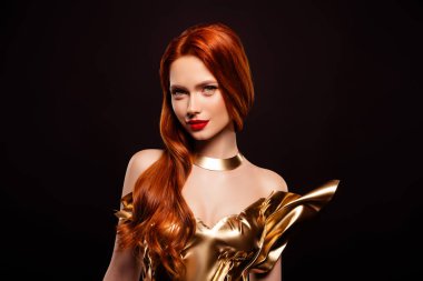 Altın sarısı elbiseli, uzun kızıl saçlı güzel bir kadın. Zarafet, kadınlık, cazibe ve entelektüellik sergiliyor. Karanlık bir stüdyo arka planında büyüleyici bir portrede..