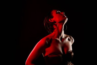 Çekici, genç, seksi bir kadının fotoğrafı. Siyah arka planda neon kırmızısı renkli, modaya uygun bir elbise..