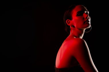 Çekici genç kadın parti dansçısının fotoğrafı. Siyah arka planda neon kırmızısı giyinmiş şık bir elbise..