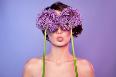 Parlak, güzel, çıplak bir kadının fotoğrafı. Çiçekler, kapalı gözler. İzole edilmiş menekşe rengi bir öpücük..