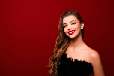 Dalgalı kahverengi saçlı, gülümseyen, izole edilmiş kırmızı arka planda neşeli bir kadın fotoğrafı..