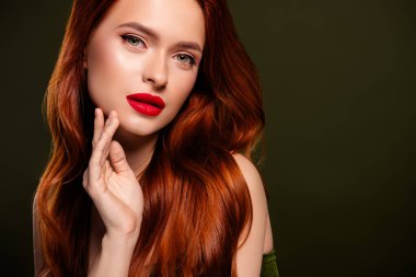 Zengin, parlak kızıl saçlı bir kadının portresi. Kırmızı dudak parlatıcısının tadını çıkarıyor. Boş, tenha haki rengi arka plan..
