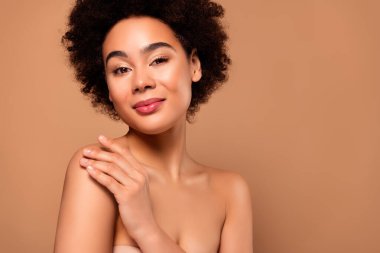 Çekici bir kadının fotoğrafı pürüzsüz tenine dokunuyor. Bej renkli arka planda izole edilmiş doğal güzellik..