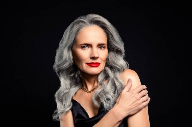 Gri saçlı, güzel, olgun bir kadın zarif makyaj ve takılar takıyor, büyüleyici bir ortamda büyüleyici bir çekicilik ve zarafet sergiliyor..