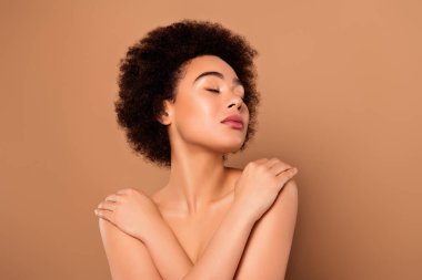 Rüya gibi, nazik, çekici bir kadının fotoğrafı. Kollarını yakın tut. Bej rengi arka planda izole edilmiş göğüs kafesi..