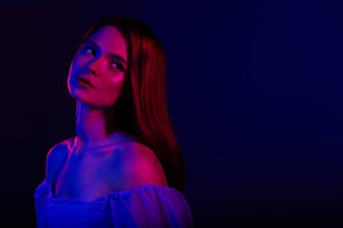 Dramatik mavi ve kırmızı ışıklı genç bir kadının portresi modern ve büyüleyici bir atmosferle güzellik, tarz ve kadınlığı vurguluyor..