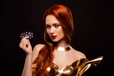 Göz kamaştırıcı bir genç kadın göz kamaştırıcı kızıl saçlar, altın bir elbise ve dikkat çekici bir karanlık arka plan karşısında duran kumarhane fişleri. Entelektüellik, tarz ve cazibe..