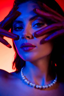 Şık makyajlı genç bir kadın modelin portresi, pembe ve mavi tonlarda gerçeküstü ışıklar sergiliyor. Zarafet ve güzelliği büyüleyici ve sanatsal bir duygusal çekiciliği var..