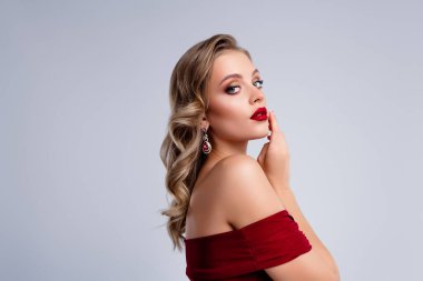 Göz kamaştırıcı güzel bayan kameraya bakıyor. Gri arka planda baştan çıkarıcı, cilveli dudaklar hissediyor..