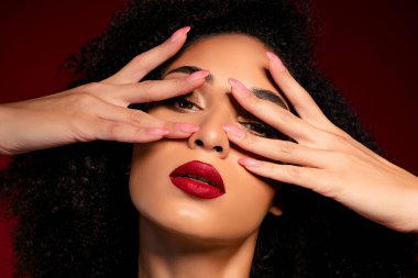 Çekici ve şık bir bayan elleri ile yüzünü kapatıyor. Kırmızı arka planda flört etmek cazip geliyor..