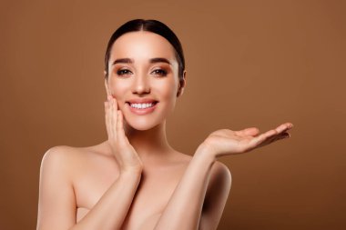 Muhteşem modelin portresi. Çıplak yüz makyajı yok. Bej arkaplanda boş bir pankart sunuyor..