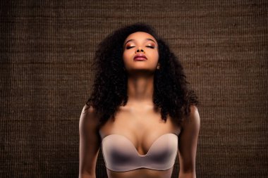 Göz alıcı makyajlı, kıvırcık saçlı, bireyselliği ve çağdaş güzelliği sembolize eden zarif genç bir kadının sunumu.