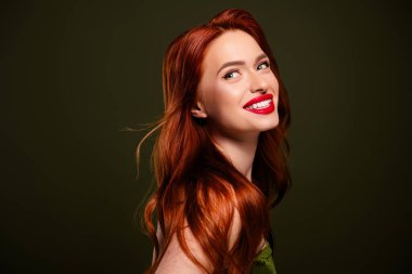 Göz kamaştırıcı rüya gibi kızıl saçlı kadının portresi kırmızı pokatif görünüşün tadını çıkarıyor izole edilmiş haki rengi arka plan..
