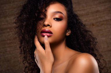 Güzel bir genç kadın kusursuz makyaj yapıyor ve şehvetli saçları var. Zarafetini ve çekiciliğini zarif ve sofistike bir pozla ön plana çıkarıyor..