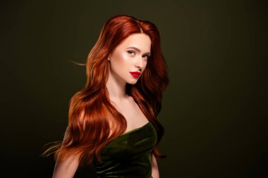 Zengin, parlak kızıl saçlı bir kadının portresi. Kırmızı dudak parlatıcısının tadını çıkarıyor. Boş, tenha haki rengi arka plan..