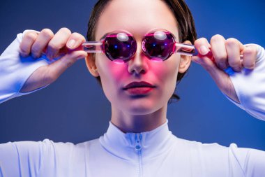 Koyu renk saçlı genç bir kadın model şık bir şekilde poz veriyor, neon renkli aksesuarlar takıyor ve parlak, aydınlık bir arkaplan karşısında modern moda ve eşsiz sanatsal ifadeyi ön plana çıkarıyor..