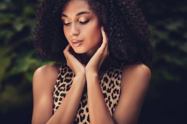 Leopar desenli kıyafet giyen, doğal güzelliğini, çekiciliğini ve özgüvenini sergileyen, yemyeşil arka planda yaşayan güzel bir kadının yakın çekimi..