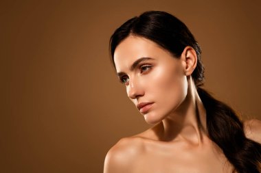 Sade bir ortamda kusursuz bir ten ve güzelliği vurgulayan esmer bir kadının yakın çekimi.