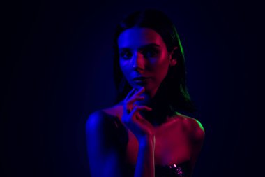 Modern fotoğrafçılıkta stil, güzellik ve anlamlı görsel kavramları vurgulayan, karanlık bir arka plandaki neon ışıklarıyla aydınlatılan bir kadın modeli.