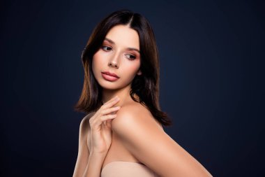 Genç bir kadın modelin portresi doğal güzelliği sergiliyor, zarif duruşu olan minimal makyaj yapıyor. Mavi arka plan, esmer saçı ve nazik yüz hatları, sofistike bir hava yaratıyor..