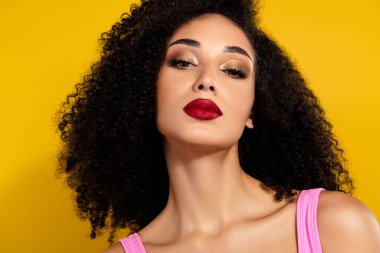 Göz kamaştırıcı makyajı, stil saçı ve pürüzsüz derisi olan göz kamaştırıcı bir kadının canlı sarı bir arka planda yakalandığı profesyonel bir görüntü. Güzellik, moda, zarafet ve modern tarz temaları için mükemmel..