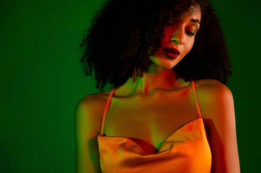 Etkileyici ışıklandırması ve büyüleyici cazibesi olan zarif genç bir kadının zarif portresi, canlı yeşil bir arka plana karşı. Zarif bir görünüm sergiliyor ve çağdaş moda ve güzelliği kutluyor..