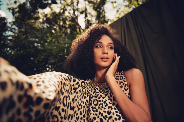 Genç bayan model şık bir leopar desenli kıyafet giyiyor. Cazibesi ve zarafeti var. Canlı ve doğal bir arka plana sahip..