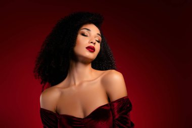 Kapalı gözlü, zarif bir bayanın fotoğrafı. Saten elbise giyerek kendini çekici hissediyor..