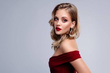 Kırmızı dudaklı güzel bayan makyajlı. Gri arka planda baştan çıkarıcı ve flört edici görünüyor..