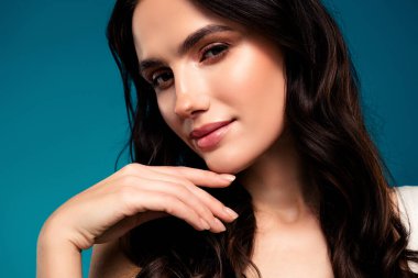 Güzel esmer kadın, berrak cilt ve şık saçlar sergiliyor, zarafet ve doğal güzellik yayıyor, profesyonel bir stüdyoda gradyan mavi bir arkaplanda poz veriyor..