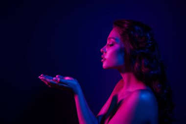 Profili olan genç bir kadın, canlı mor ve pembe neon ışıklarla aydınlanmış, modern fotojenik cazibeyle ışıldayan bir tarz ve zarafet sergiliyor..