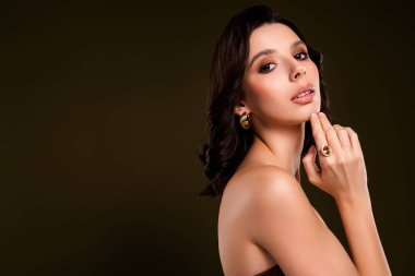 Koyu renk haki rengi bir stüdyoda şık bir pozda lüks mücevher modelliği yapan şık genç bir kadın..