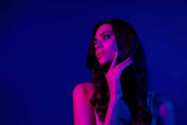 Neon ışıkta poz veren zarif genç kadın, yüz hatlarını vurgulayan, canlı renkler, ve modern güzellik estetiği..